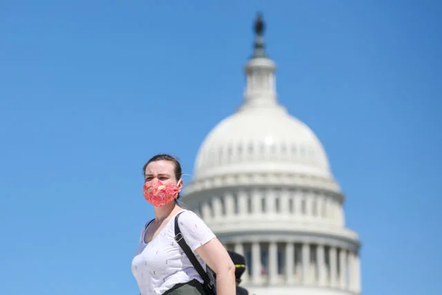 A woman wears a face mask in front of the US Capitol building