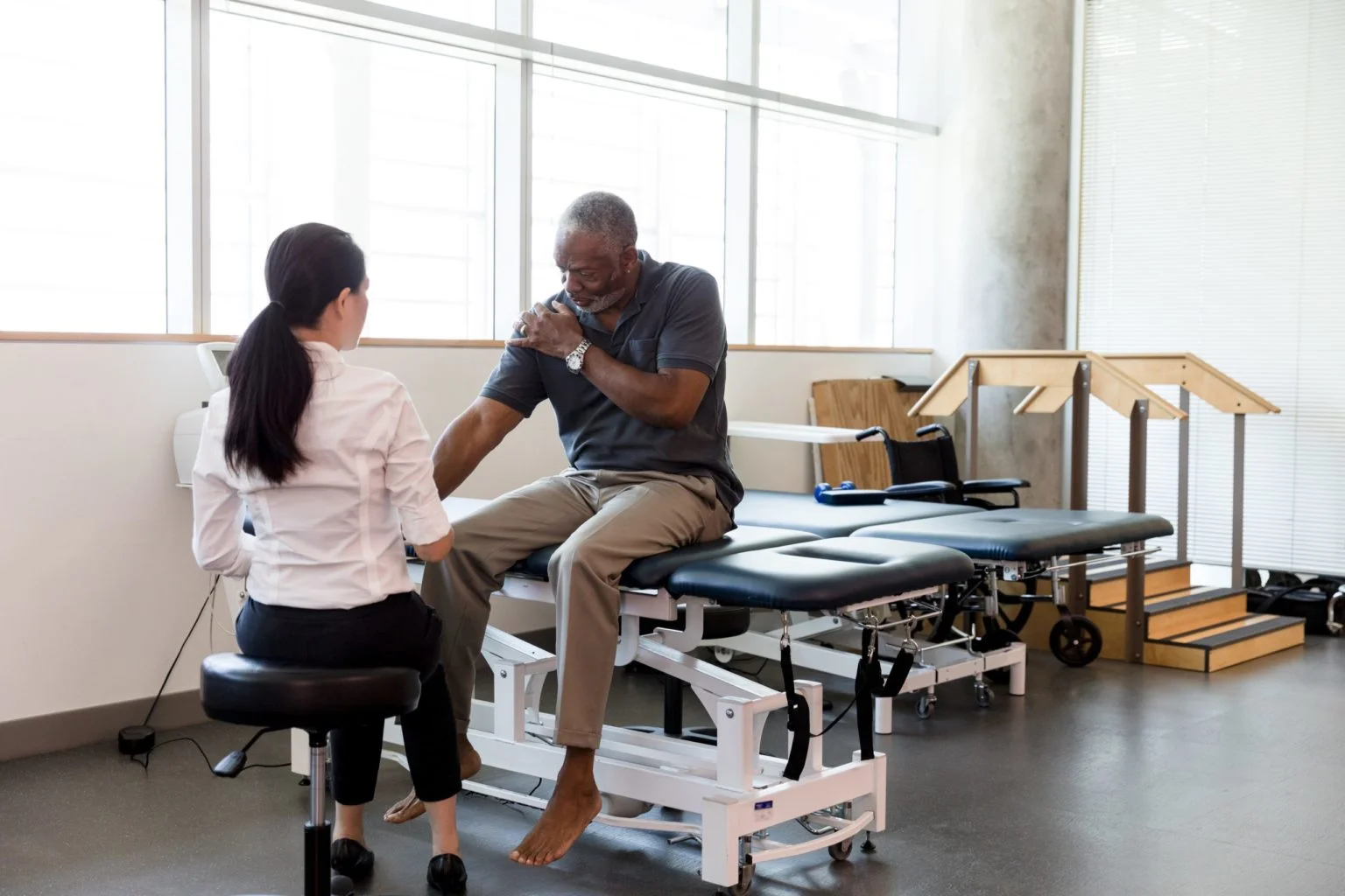 Senior man with an injured shoulder in rehab clinic