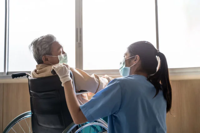 Nurse taking care of mature patient in front of window