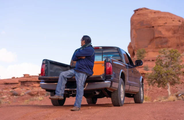 Navajo man sitting on the bed of his pick-up truck in Monument Valley
