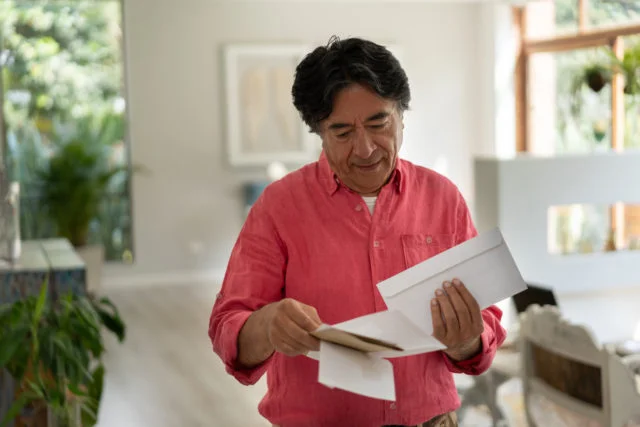 Cheerful senior man at home looking at his mail