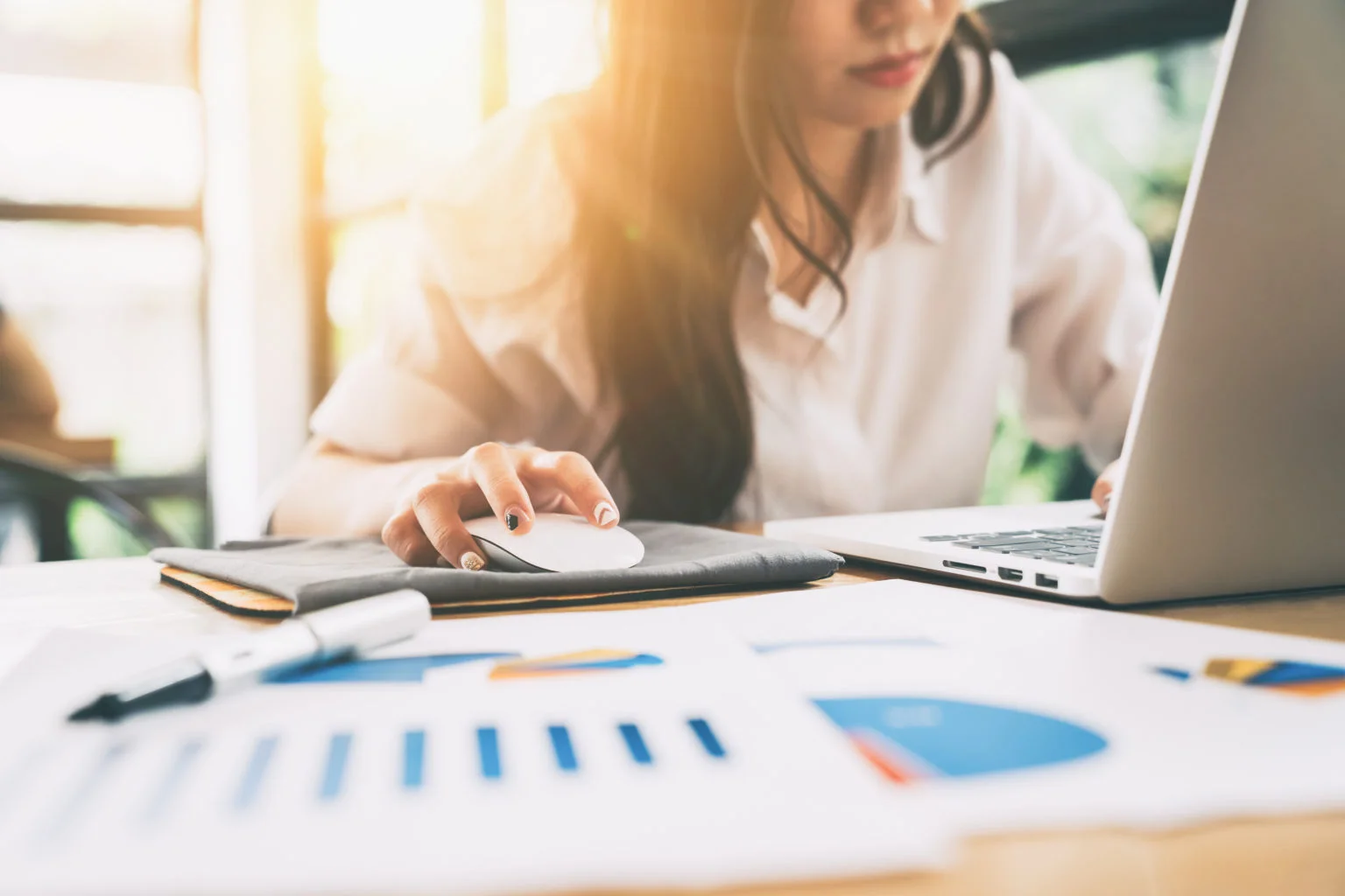 Young casual woman sitting working on laptop with business data