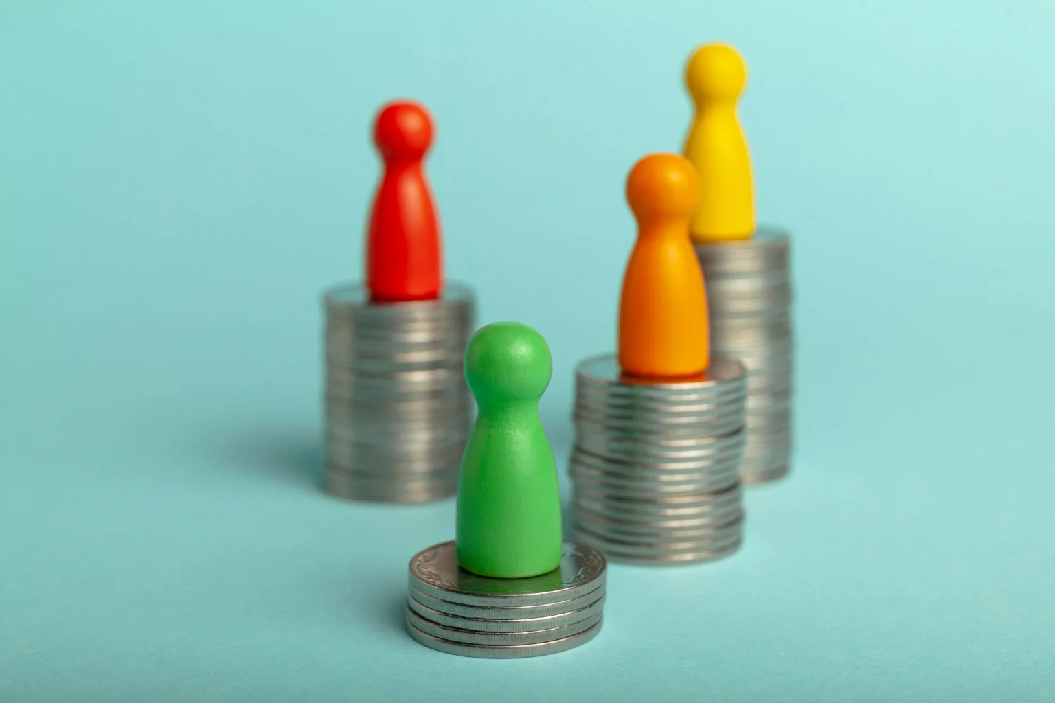 Wooden figures on different size coin stacks