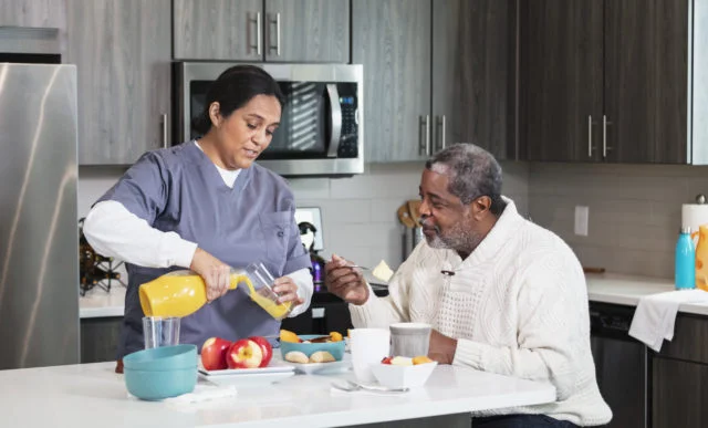 Caregiver with senior African-American man in kitchen